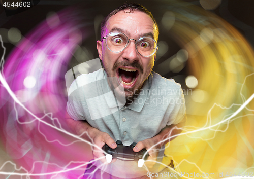 Image of Enthusiastic gamer. Joyful young man holding a video game controller