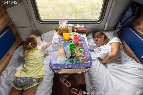 Image of The situation on the train, mom and daughters are sleeping on the lower shelves in the car
