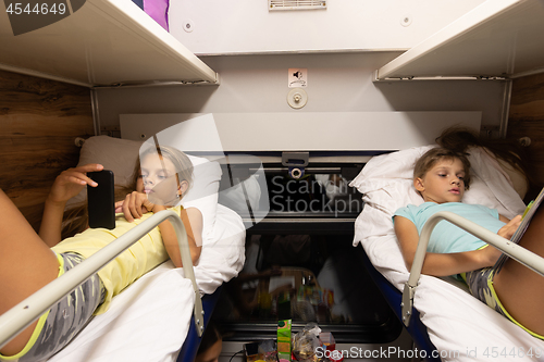 Image of Children on the upper shelves of a reserved seat car do different activities