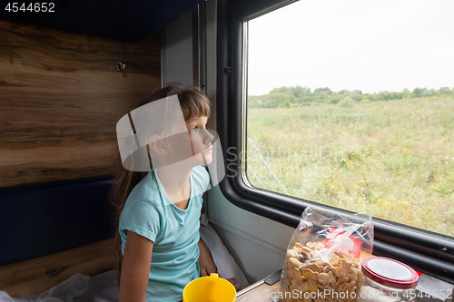 Image of Girl sitting in a reserved seat wagon looks tiredly out the window