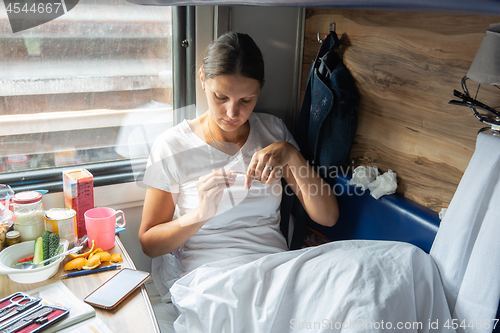 Image of The girl cuts her nails in the reserved seat of the train