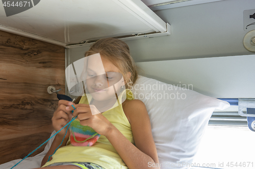 Image of Girl knitting lying on the top shelf of the car