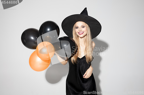 Image of Young woman in hat as a witch on white background