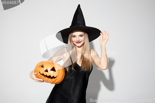 Image of Young woman in hat as a witch on white background