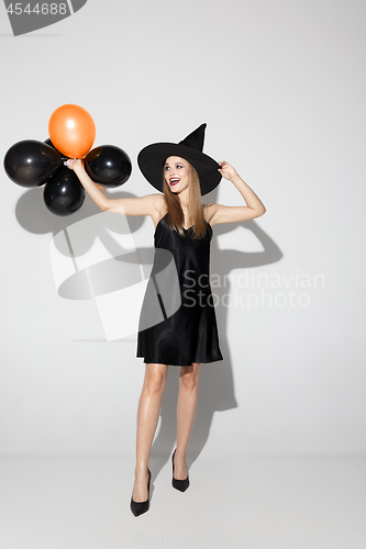 Image of Young woman in hat as a witch on white background