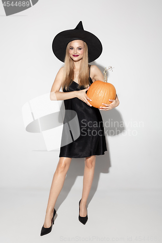 Image of Young woman in hat as a witch on white background