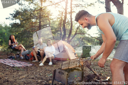 Image of Party, camping of men and women group at forest. They relaxing, singing a song and cooking barbecue