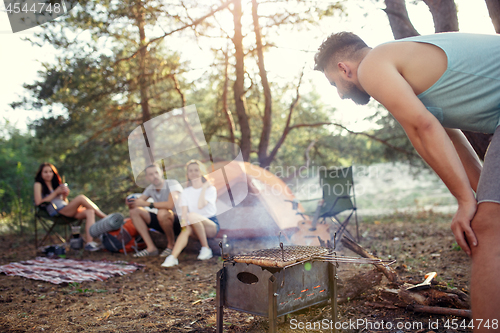 Image of Party, camping of men and women group at forest. They relaxing, singing a song and cooking barbecue