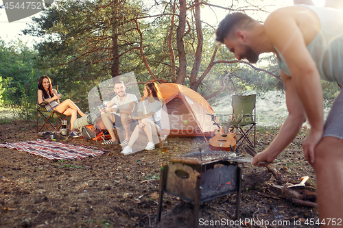 Image of Party, camping of men and women group at forest. They relaxing, singing a song and cooking barbecue