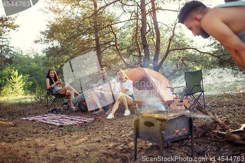 Image of Party, camping of men and women group at forest. They relaxing, singing a song and cooking barbecue