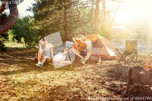 Image of Party, camping of men and women group at forest. They relaxing, singing a song