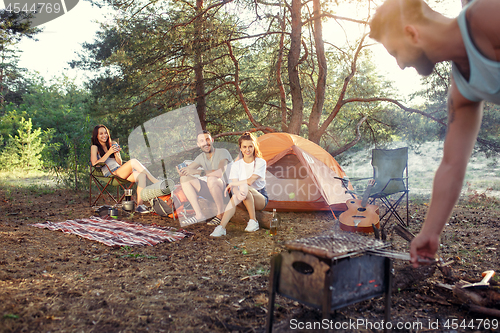 Image of Party, camping of men and women group at forest. They relaxing, singing a song and cooking barbecue