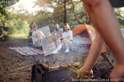 Image of Party, camping of men and women group at forest. They relaxing, singing a song and cooking barbecue