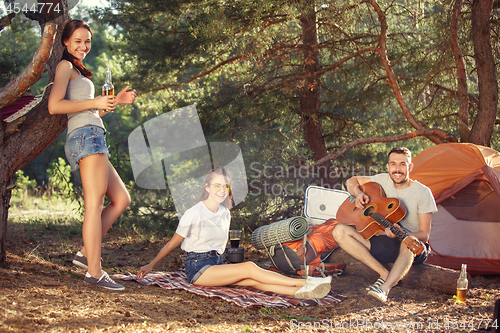 Image of Party, camping of men and women group at forest. They relaxing, singing a song