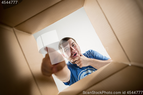 Image of Man unpacking and opening carton box and looking inside