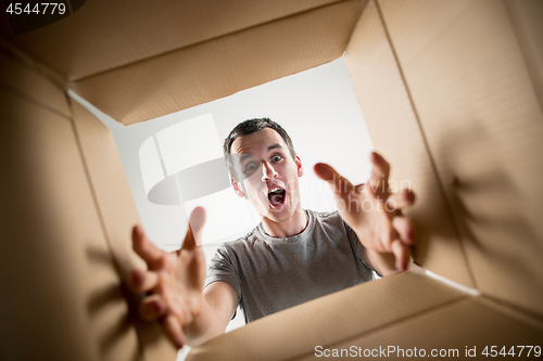 Image of Man unpacking and opening carton box and looking inside