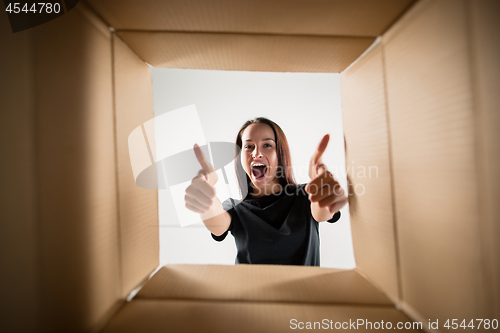 Image of Woman unpacking and opening carton box and looking inside