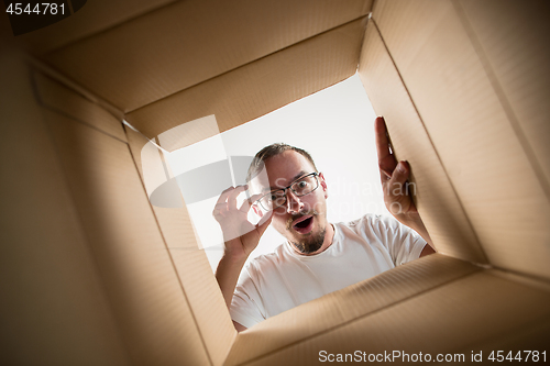 Image of Man unpacking and opening carton box and looking inside