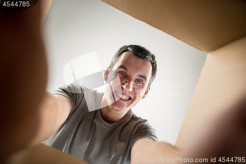 Image of Man unpacking and opening carton box and looking inside