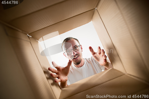 Image of Man unpacking and opening carton box and looking inside