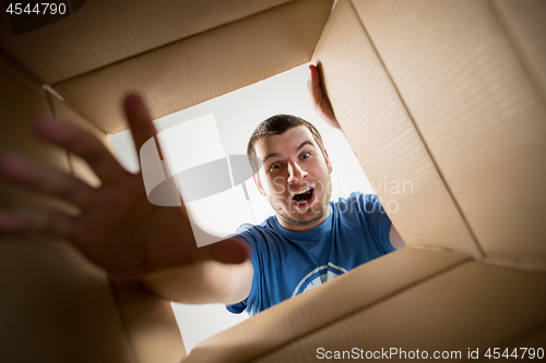 Image of Man unpacking and opening carton box and looking inside