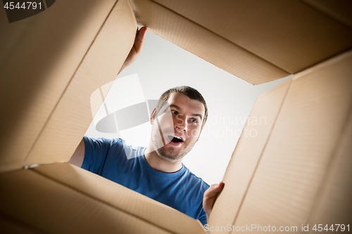 Image of Man unpacking and opening carton box and looking inside