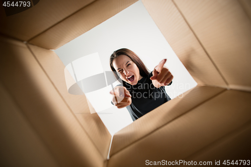 Image of Woman unpacking and opening carton box and looking inside