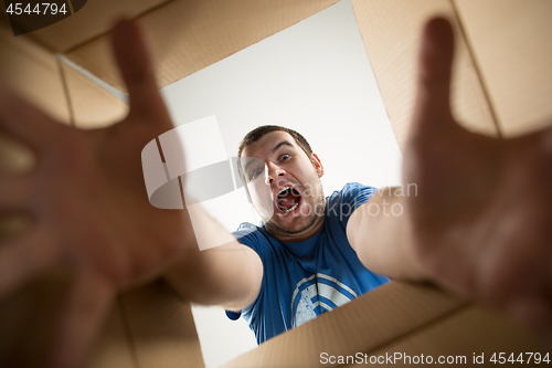 Image of Man unpacking and opening carton box and looking inside