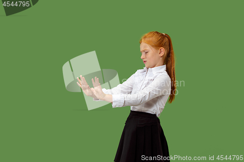 Image of Doubtful pensive teen girl rejecting something against green background