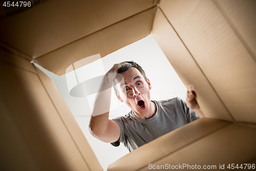 Image of Man unpacking and opening carton box and looking inside