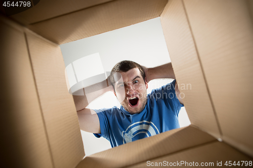 Image of Man unpacking and opening carton box and looking inside