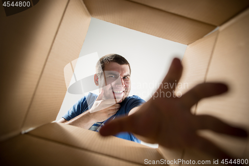 Image of Man unpacking and opening carton box and looking inside