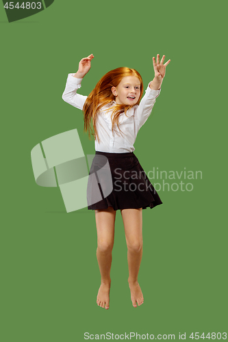 Image of Young happy caucasian teen girl jumping in the air , isolated on green background