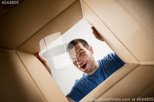 Image of Man unpacking and opening carton box and looking inside