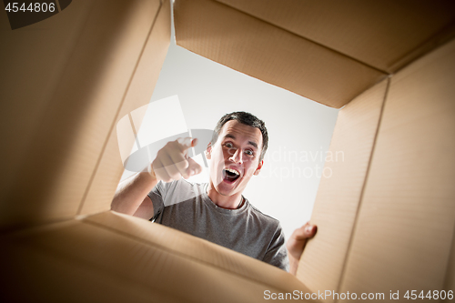 Image of Man unpacking and opening carton box and looking inside