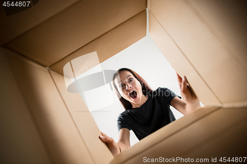 Image of Woman unpacking and opening carton box and looking inside