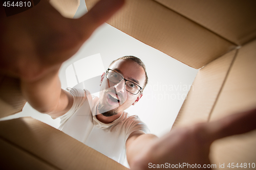 Image of Man unpacking and opening carton box and looking inside