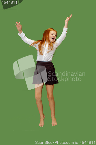 Image of Young happy caucasian teen girl jumping in the air , isolated on green background