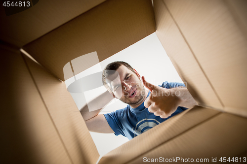 Image of Man unpacking and opening carton box and looking inside