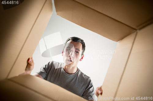 Image of Man unpacking and opening carton box and looking inside