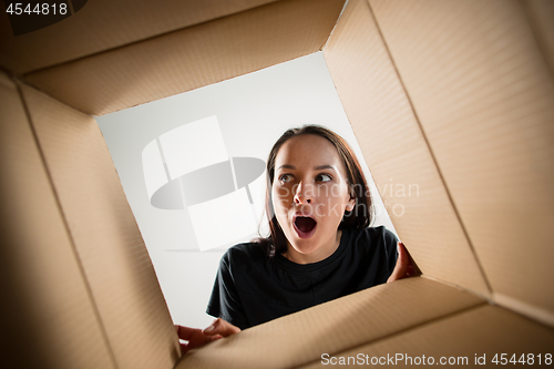 Image of Woman unpacking and opening carton box and looking inside