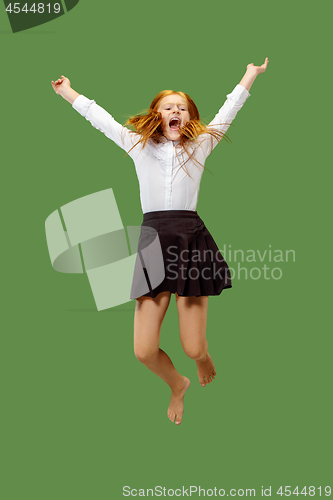 Image of Young happy caucasian teen girl jumping in the air , isolated on green background