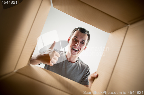 Image of Man unpacking and opening carton box and looking inside