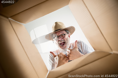 Image of Man unpacking and opening carton box and looking inside