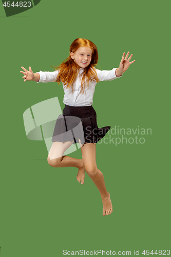 Image of Young happy caucasian teen girl jumping in the air , isolated on green background