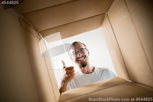 Image of Man unpacking and opening carton box and looking inside