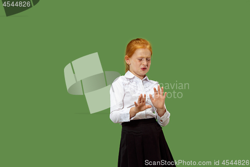 Image of Doubtful pensive teen girl rejecting something against green background