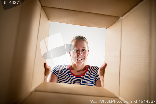 Image of Woman unpacking and opening carton box and looking inside