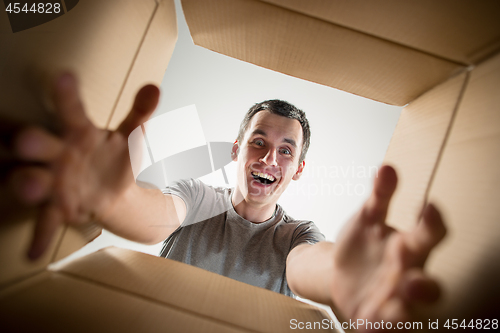 Image of Man unpacking and opening carton box and looking inside