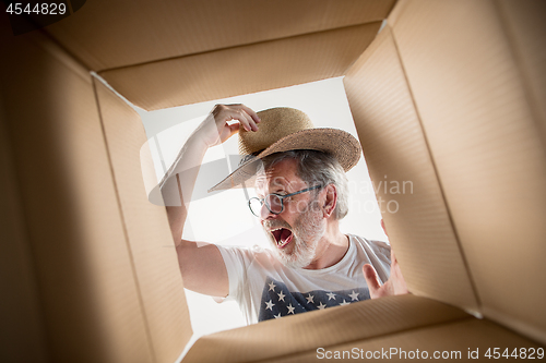 Image of Man unpacking and opening carton box and looking inside